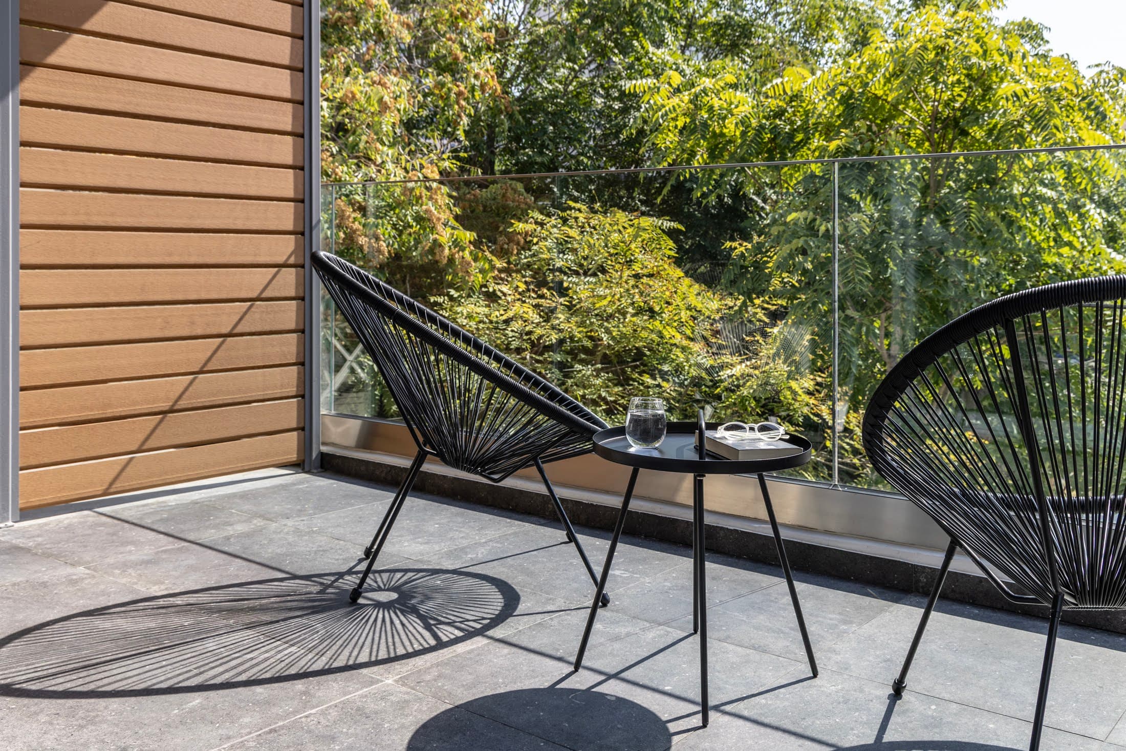Sunny balcony with two black outdoor chairs